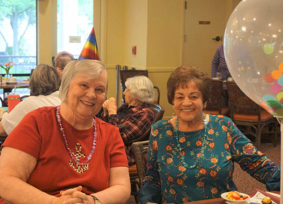 two women sitting at a table at a party  at Winding Commons Senior Living, Carmichael