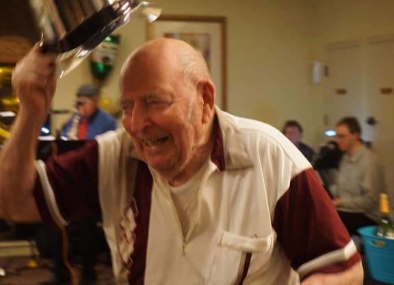 an older man sitting at a table with his hand up in the air at Winding Commons Senior Living, Carmichael, 95608