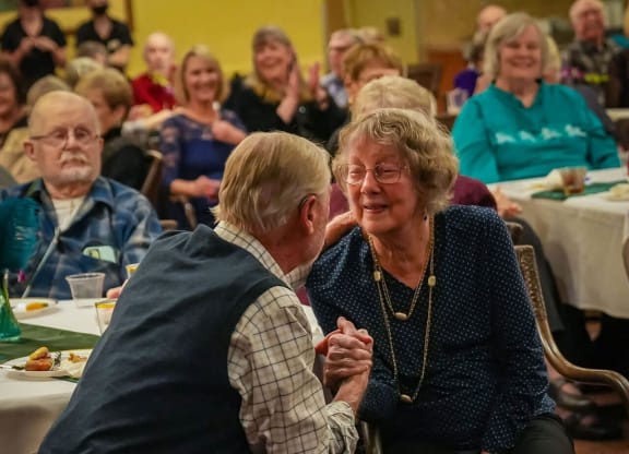a man and a woman sitting at a table talking to each other at Winding Commons Senior Living, Carmichael, California