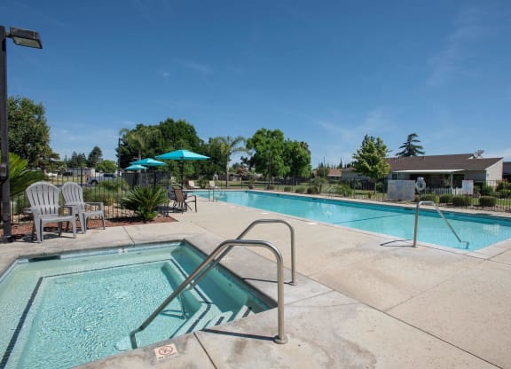our apartments have a swimming pool with chairs and umbrellas at Castle Vista Senior Duplex Community, Atwater, CA