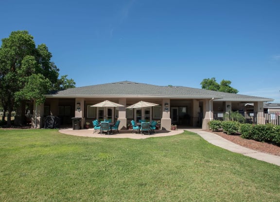 the backyard of a house with patio chairs and umbrellas at Castle Vista Senior Duplex Community, Atwater, CA