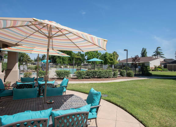 a patio with a table with chairs and an umbrella at Castle Vista Senior Duplex Community, Atwater, California