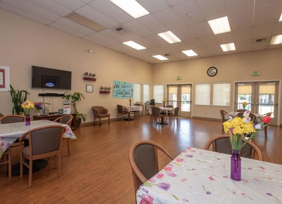 a large room with tables and chairs and a tv at Castle Vista Senior Duplex Community, Atwater, CA, 95301