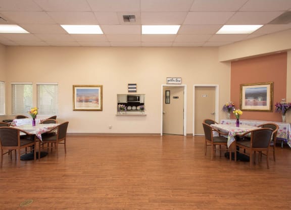 a dining room with tables and chairs in a large room with a wood floor at Castle Vista Senior Duplex Community, Atwater, CA, 95301