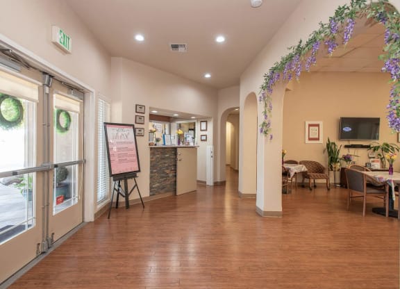 a long hallway with tables and chairs and a bulletin board on the wall at Castle Vista Senior Duplex Community, Atwater