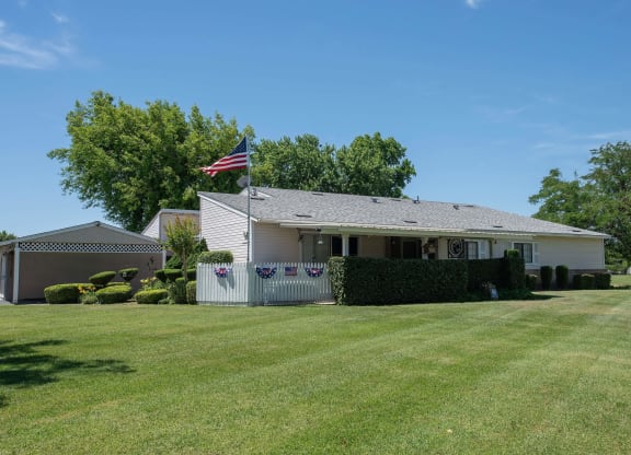 a white house with an flag flying in front of it at Castle Vista Senior Duplex Community, Atwater