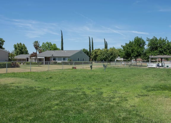 a fenced in dog park with a house in the background at Castle Vista Senior Duplex Community, Atwater, California