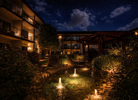 Courtyard water feature with illuminated fountains at night at Roseville Commons Senior Living Apartments, Roseville, CA 95678