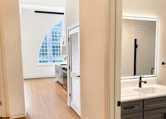 A bathroom with a sink, mirror, and wooden floors.