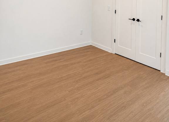 A room with a white door and wooden floor.