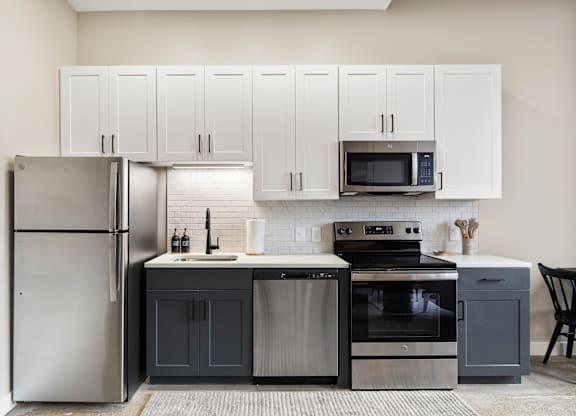 a kitchen with stainless steel appliances and white cabinets at Textile Apartments, Cincinnati, OH