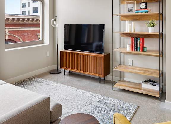 a living room with a couch and a television and a bookshelf at Textile Apartments, Cincinnati