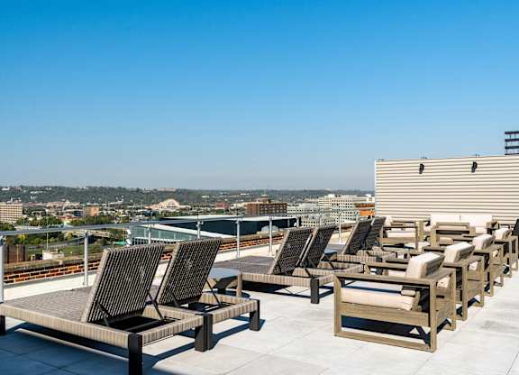 a row of lounge chairs on a roof top overlooking a city at Textile Apartments, Cincinnati