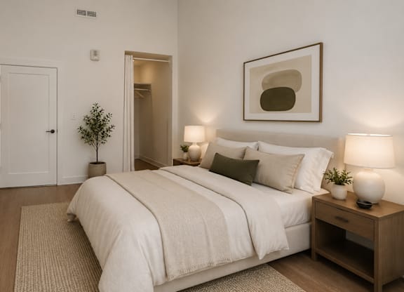A bedroom with a bed, nightstands, and a plant.