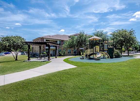 a playground in a park with a building in the background at Discovery at Craig Ranch, McKinney, Texas