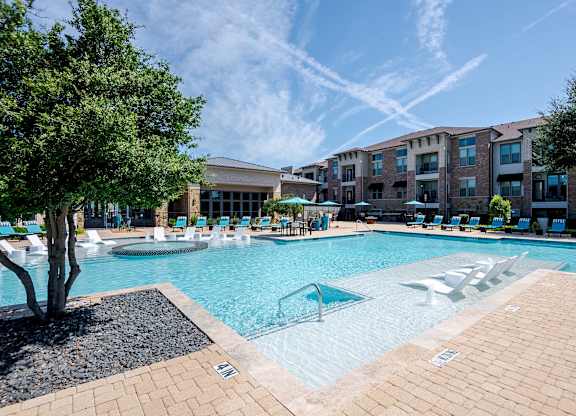 a large swimming pool with lounge chairs in front of an apartment building at Discovery at Craig Ranch, McKinney, 75070