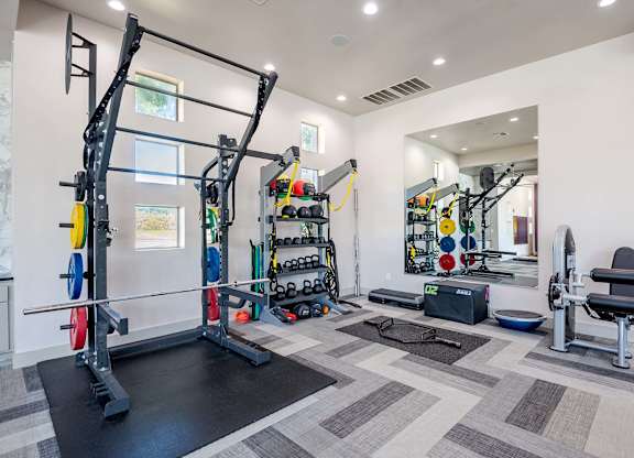 a fitness center with weights and equipment on the wall at Discovery at Craig Ranch, McKinney, TX