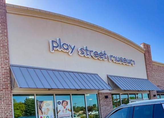 A Play Street Museum storefront with a blue sky in the background at Craig Ranch, McKinney, TX.