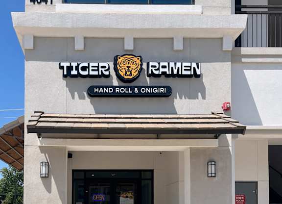 A white building with a black and gold sign that says Tiger Ramen at Discovery at Craig Ranch, McKinney, TX