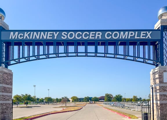 McKinney Soccer Complex entrance with a blue arch and red brick pillars at Craig Ranch, McKinney, TX