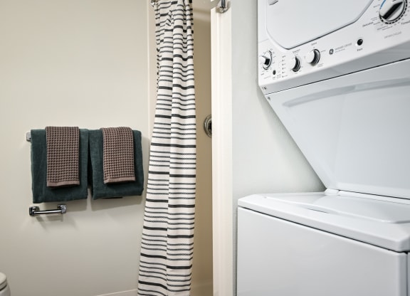 a bathroom with a washer and dryer and a towel rack next to a