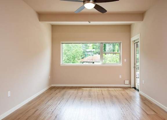 a empty living room with a window and a ceiling fan