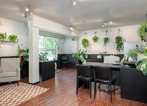 A room with a white chair and a table with a vase on it.