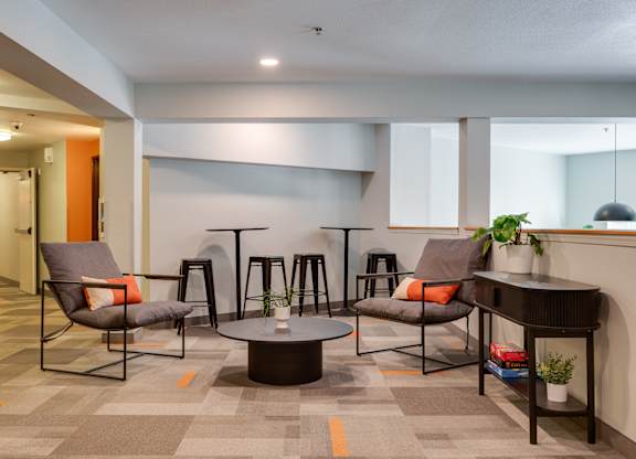 A modern lounge area with grey chairs and a round table.