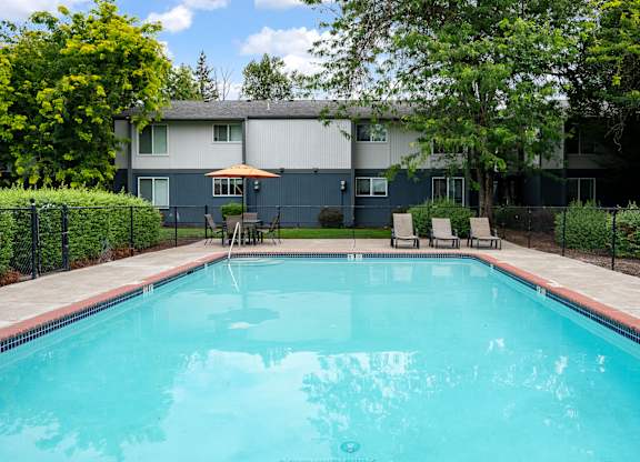A swimming pool surrounded by a fence and trees.