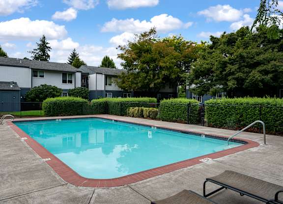 A small pool with a bench and a fence around it.