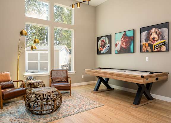 A room with a pool table and three framed pictures on the wall.