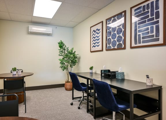 a conference room with a table and chairs and paintings on the wall