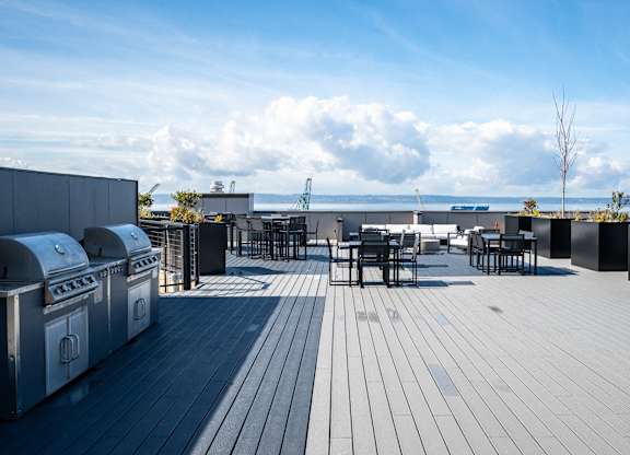 a rooftop patio with tables and chairs and a view of the ocean