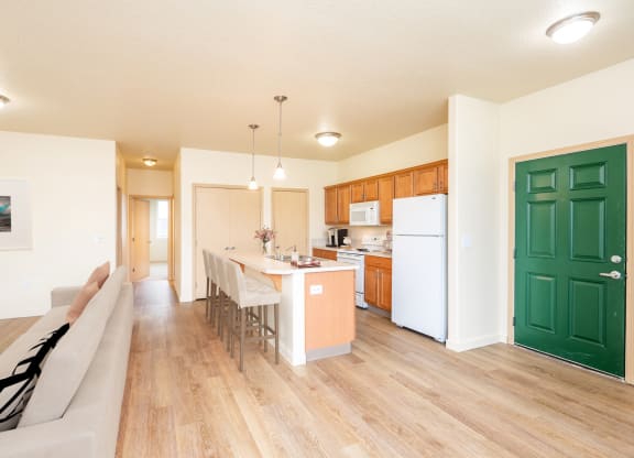an open kitchen and living room with a dining table and a refrigerator