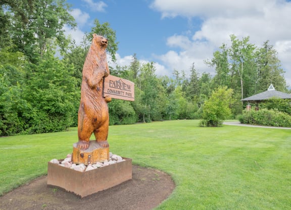 a statue of a bear holding a sign in a park