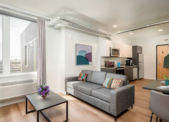 A living room with a grey couch, a coffee table, and a painting on the wall.