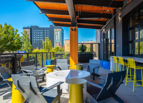 a rooftop patio with tables and chairs and a view of the city