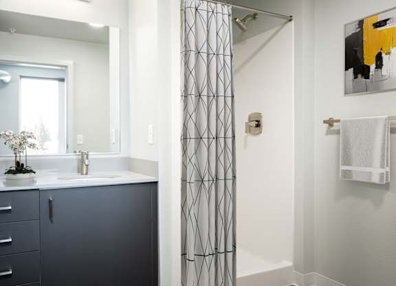 A bathroom with a white sink and a grey cabinet.