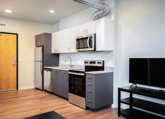 a kitchen with stainless steel appliances and a tv in a apartment
