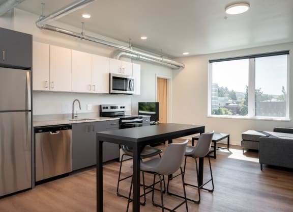a kitchen and living room with a refrigerator and a table and chairs