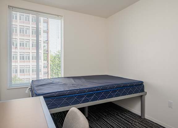 A bed with a blue mattress is in a room with a window.
