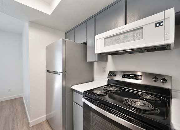 A kitchen with a stove, refrigerator, and microwave.
