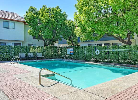A swimming pool surrounded by a fence and trees.