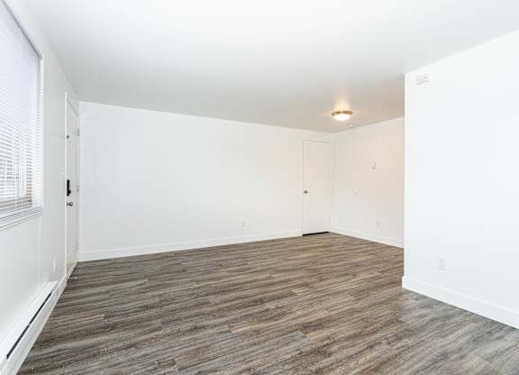 A room with wooden flooring and white walls.