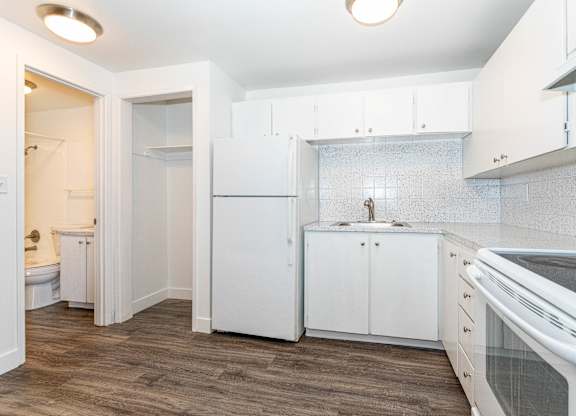 A kitchen with white cabinets and a wooden floor.