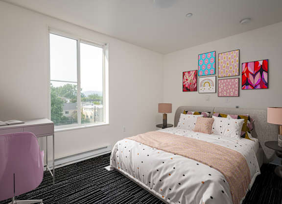 A bedroom with a large bed, a desk with a chair, and a window with a view of the outdoors.
