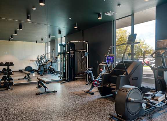 A gym with a variety of equipment including treadmills, weights, and exercise machines.