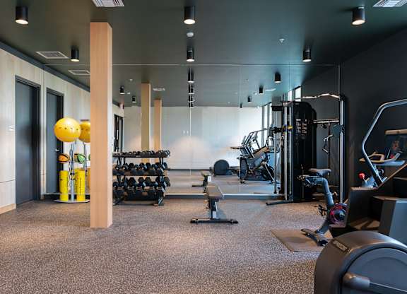 A gym with a variety of equipment including weights and cardio machines.