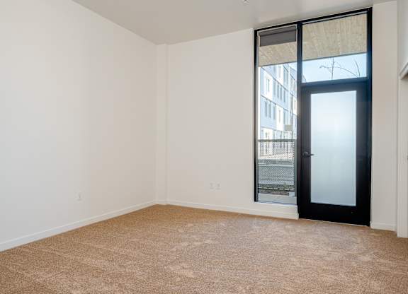 A room with a carpeted floor and a sliding glass door.