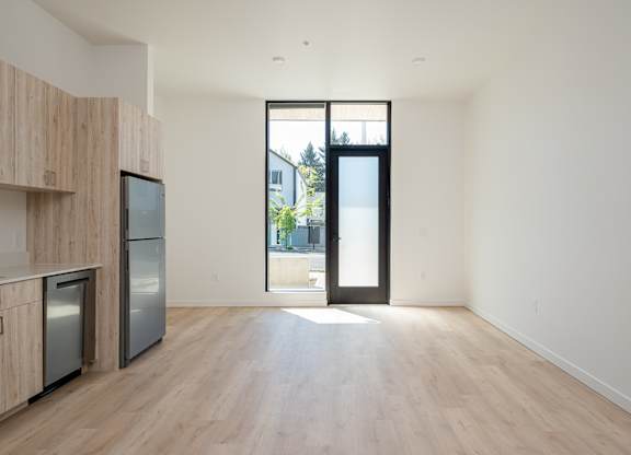 A kitchen with wooden cabinets and a black door leading outside.